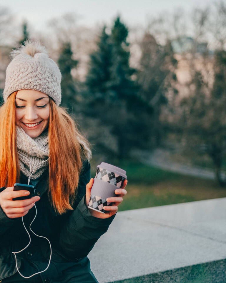 Frau im Winter-Outfit freut sich über ihren neuen Handytarif